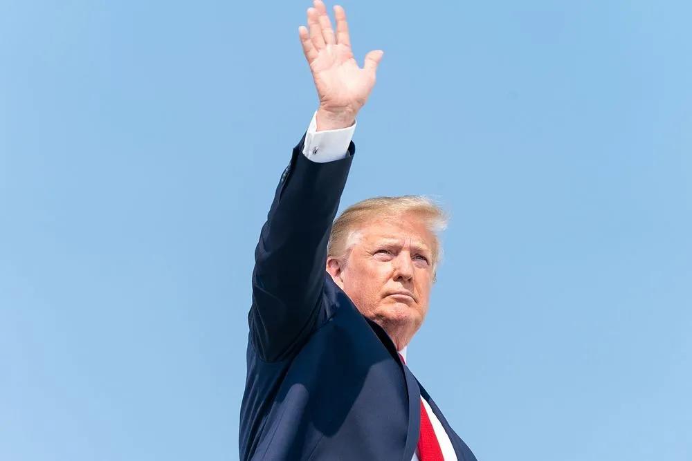 US president Donald Trump waving in front of a clear blue sky
