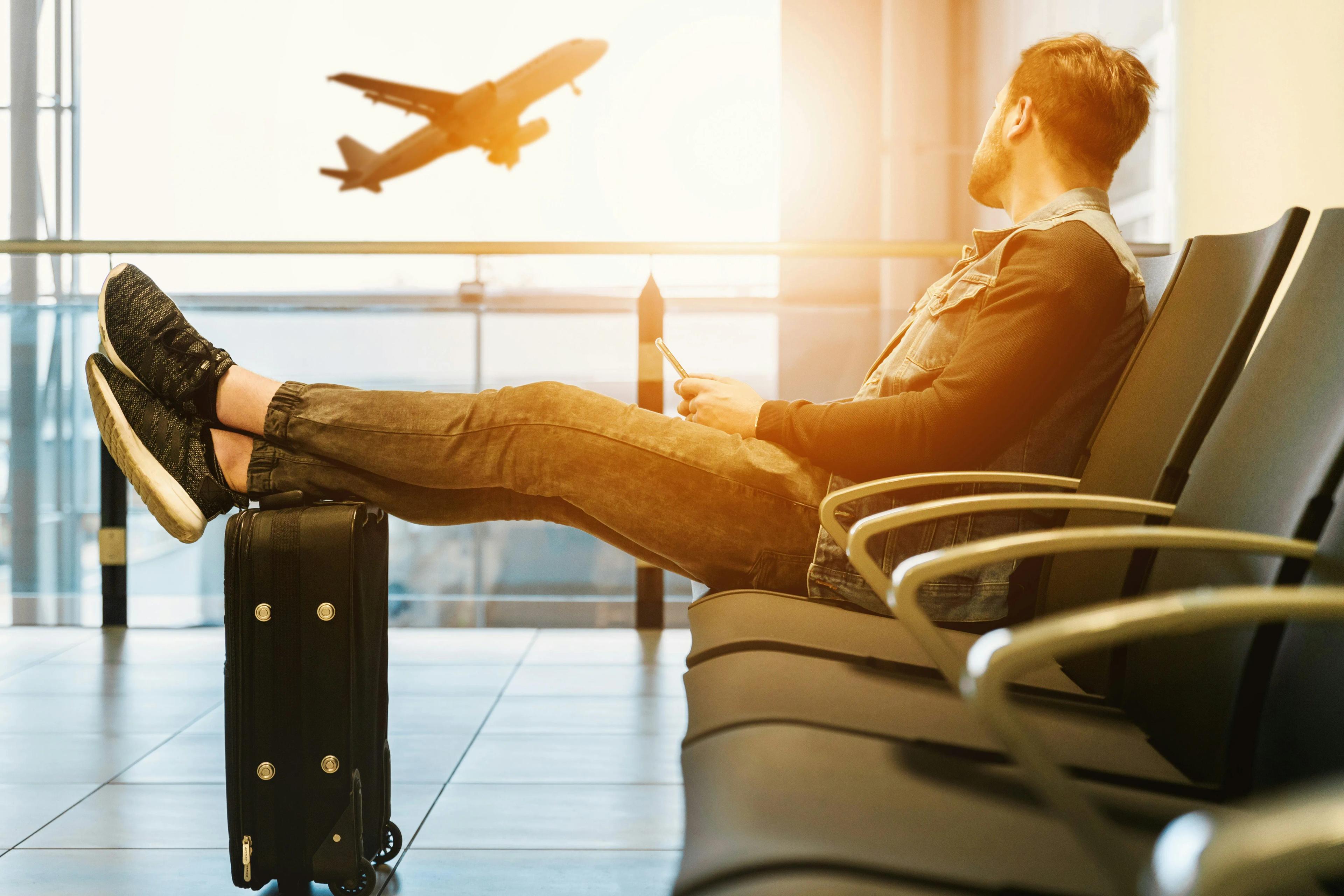 A man watching a plane take off through airport window
