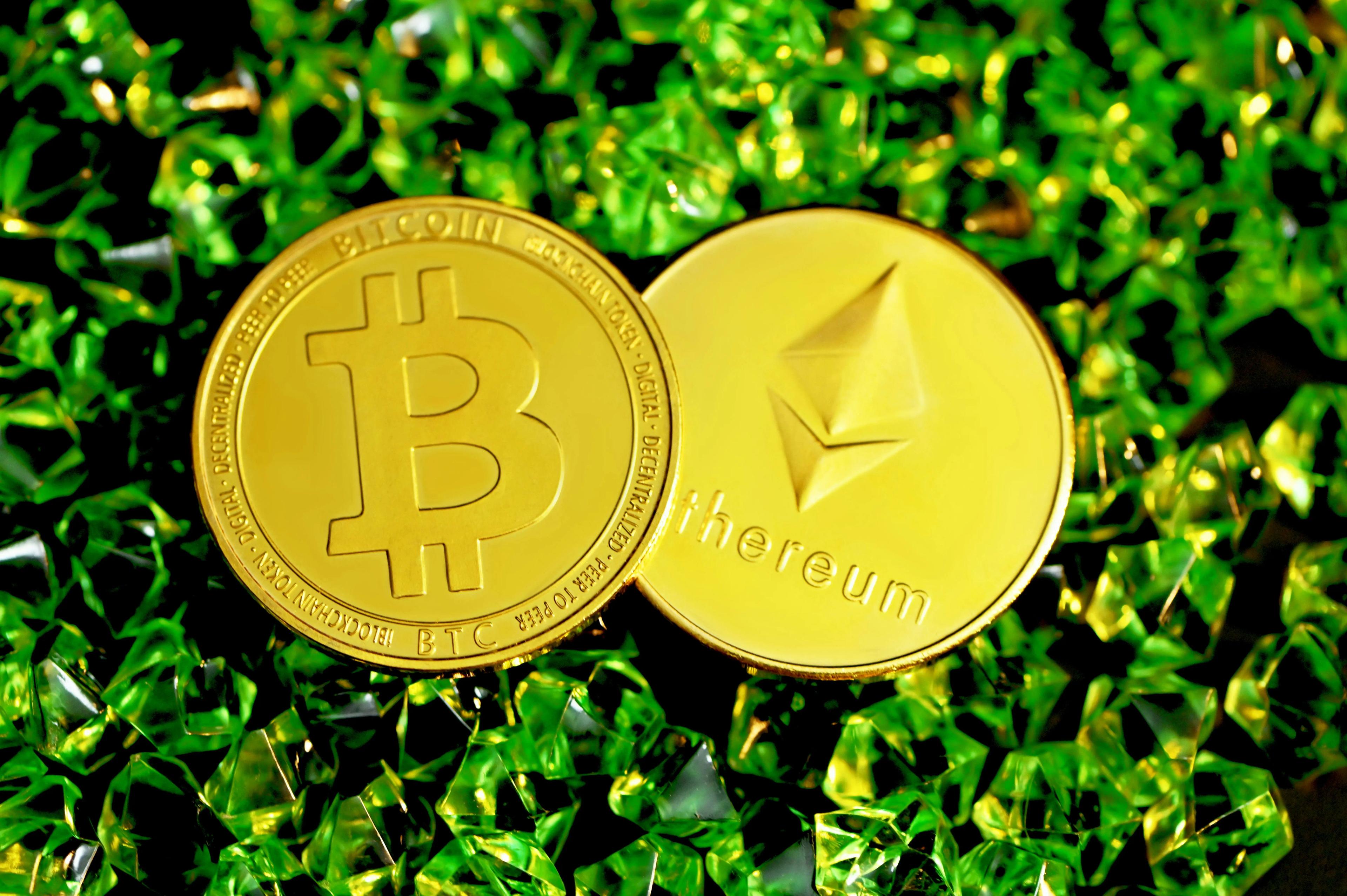A Bitcoin and an Ethereum coin together on green crystals