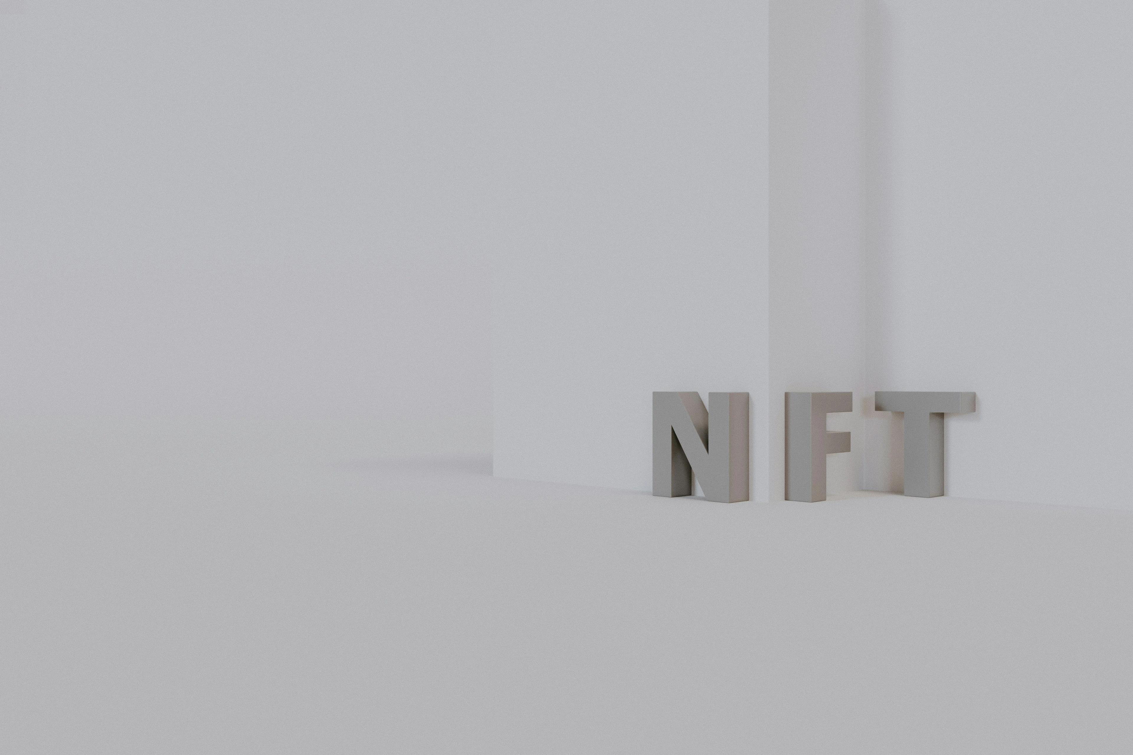 A white wall with grey letters standing against it spelling NFT