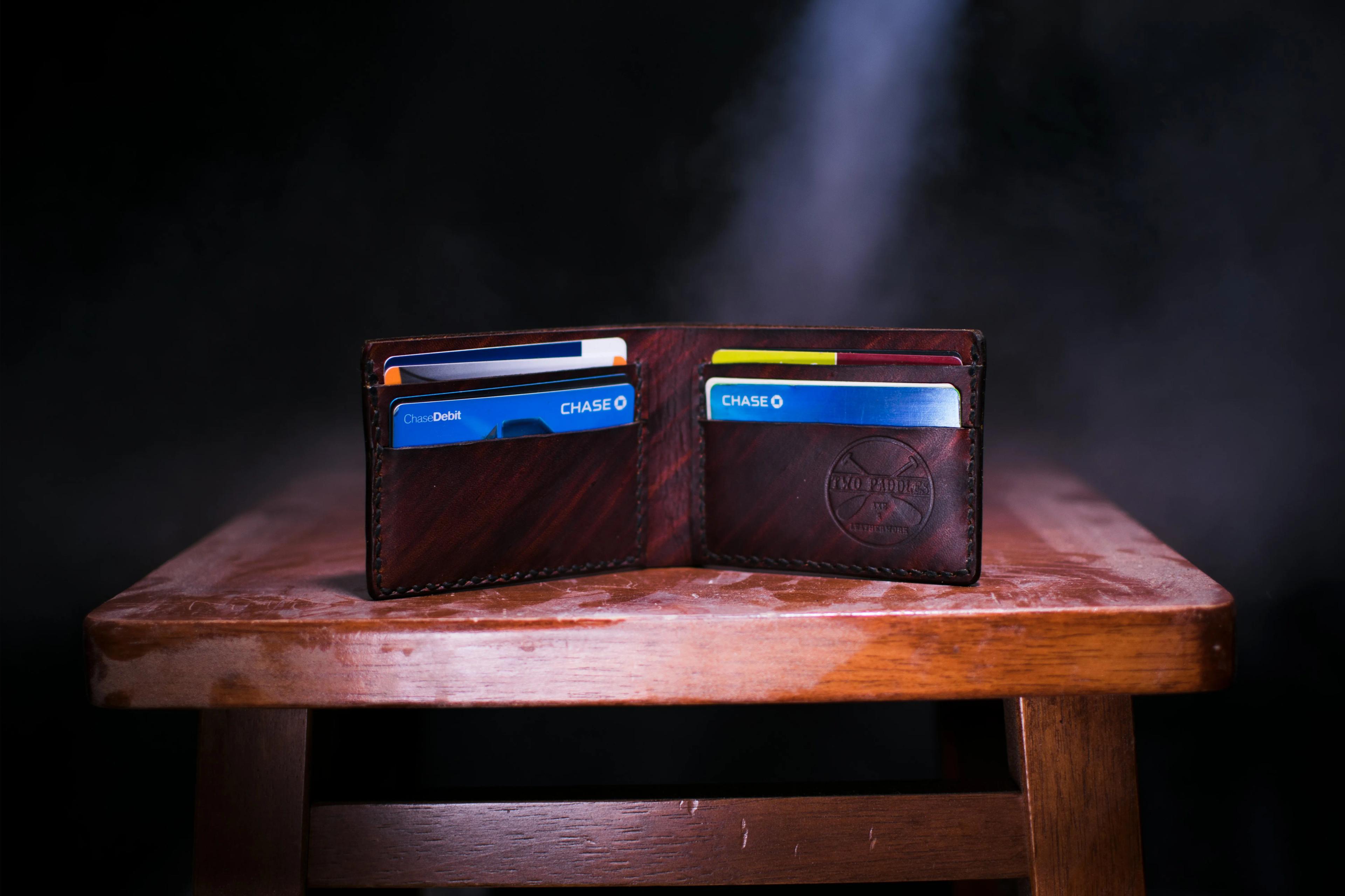 An open leather wallet sits on a wooden table